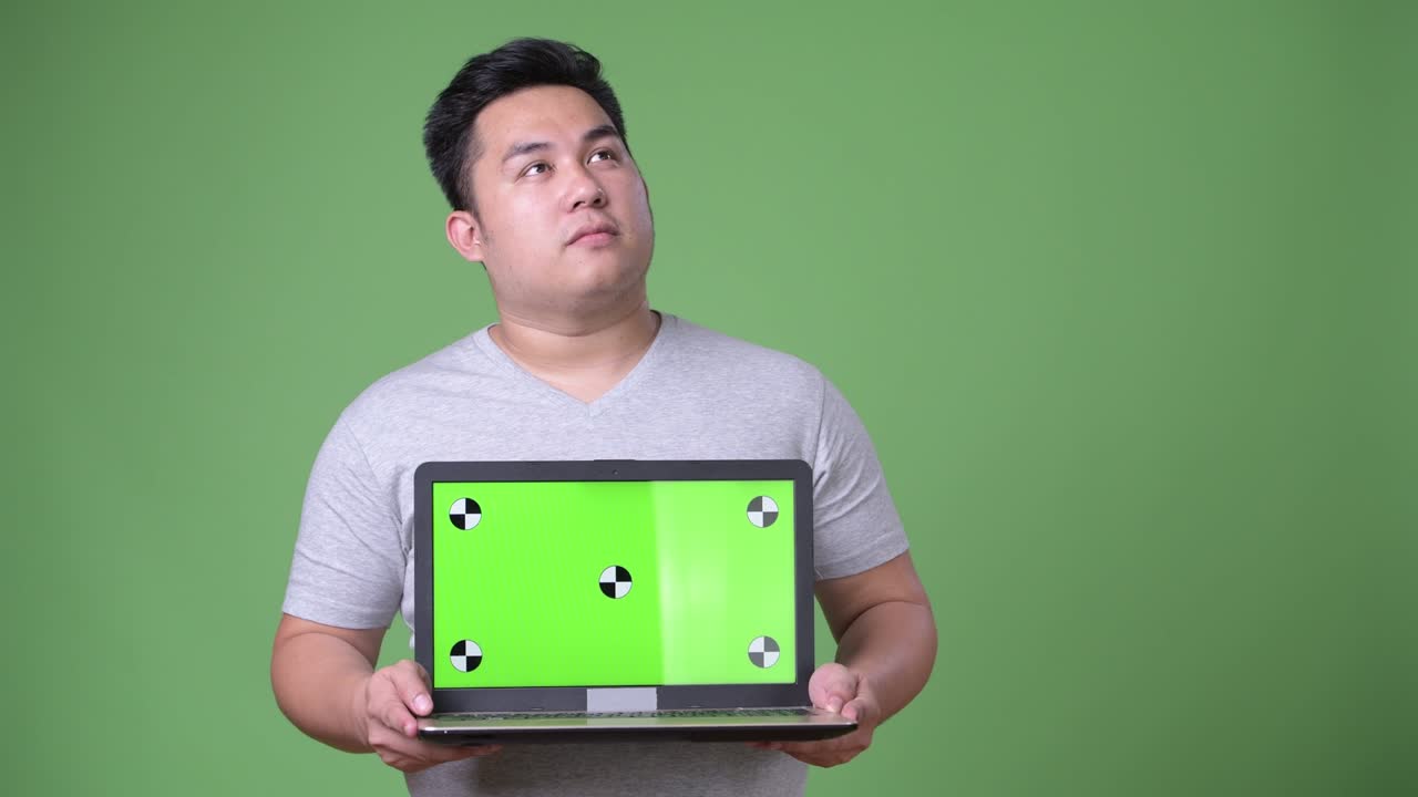 초록색 배경에 젊은 잘생긴 과체중 아시아인