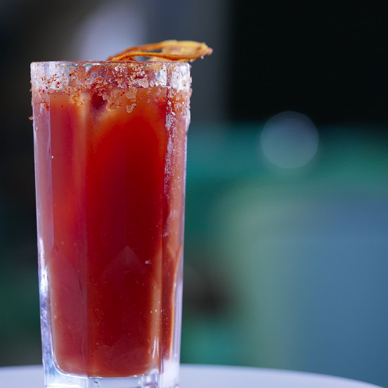 Cocktail rossi in un bicchiere alto con cristalli di sale sul bordo. Rotazione della bevanda con una fetta di arancia essiccata sopra. Primo piano. Sfondo sfocato