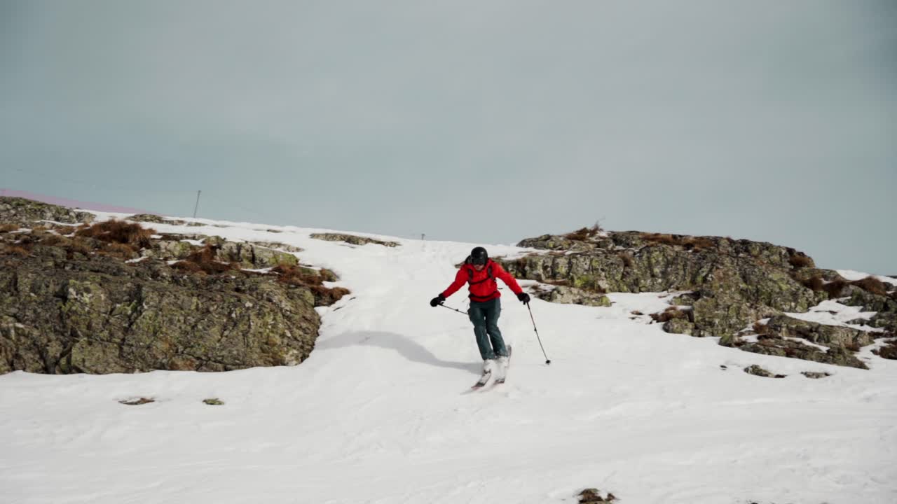 freeskier salta por la ladera rocosa durante la temporada de invierno