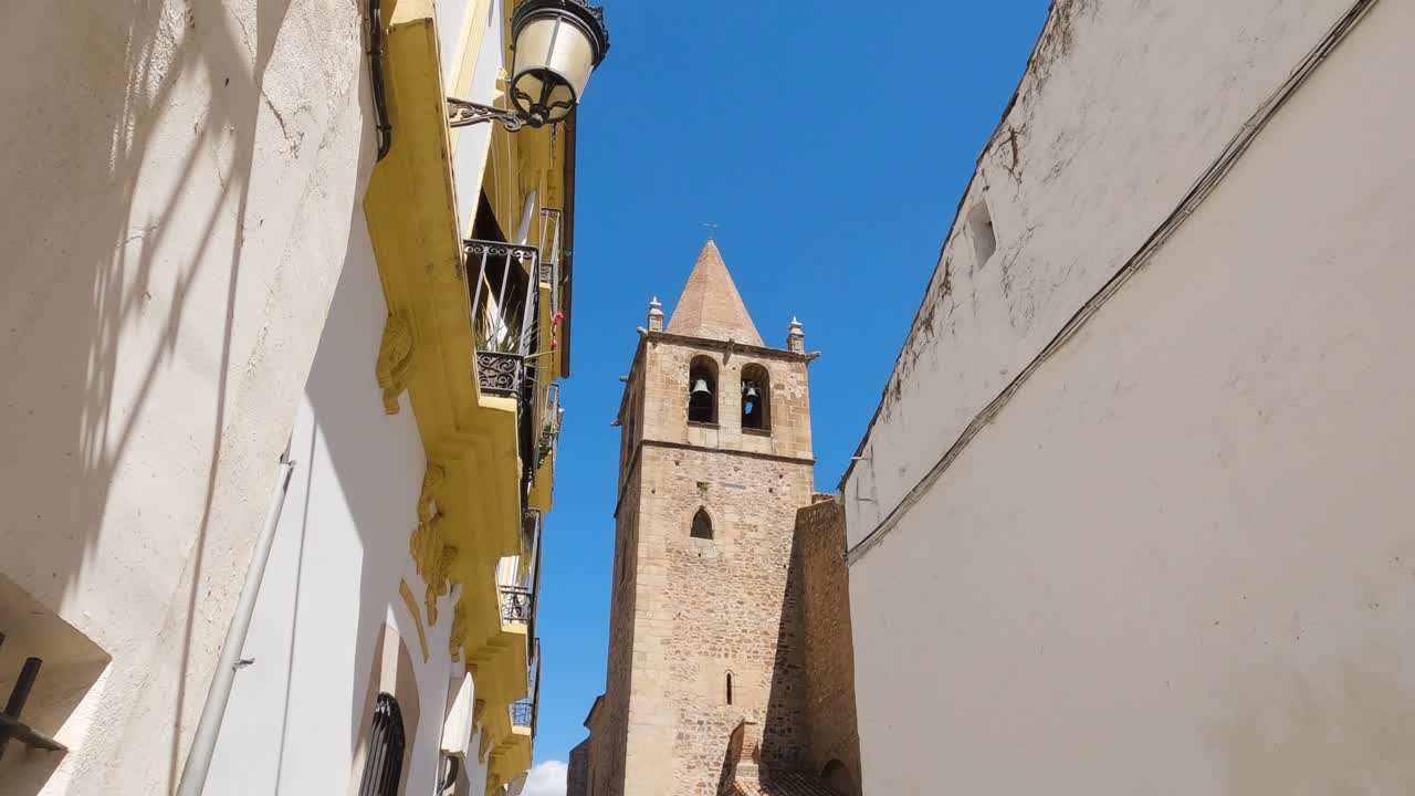 View Tower of Santiago el Mayor church from a street alley, C&aacute;ceres, Spain