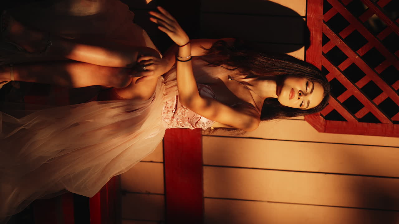 VERTICAL Attractive sensual female sitting in front of rustic panel wood wall enjoying golden sunset glow on her skin