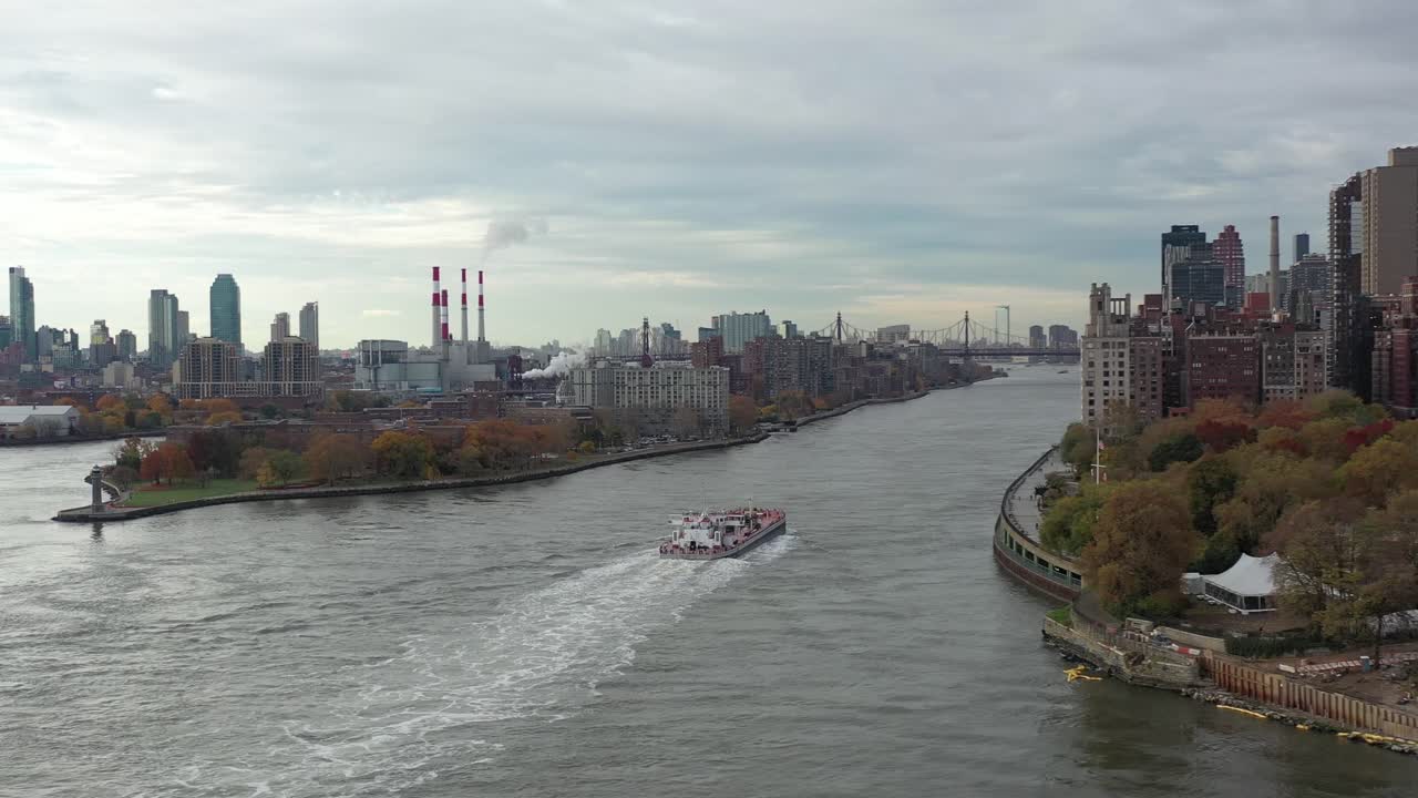맨해튼과 루즈벨트 섬 사이의 뉴욕 동쪽 강을 따라 유조선을 따라 드론이 회전합니다.
