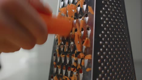 man shredding a carrot with a grater cooking