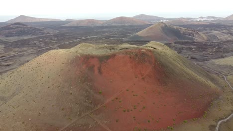 aerial drone footage of a huge red volcano and a solitary road in canary islands, spain