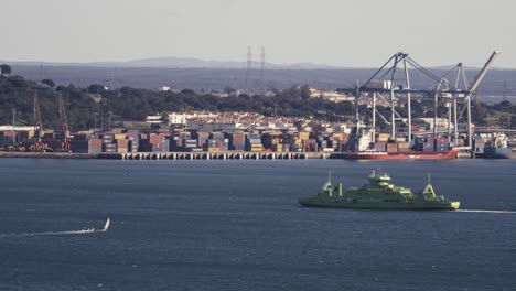 Costa-Oeste-De-Portugal,-Barco-Flotante-Verde,-Contenedores-En-El-Fondo,-Vista-Estática-De-Día-Soleado