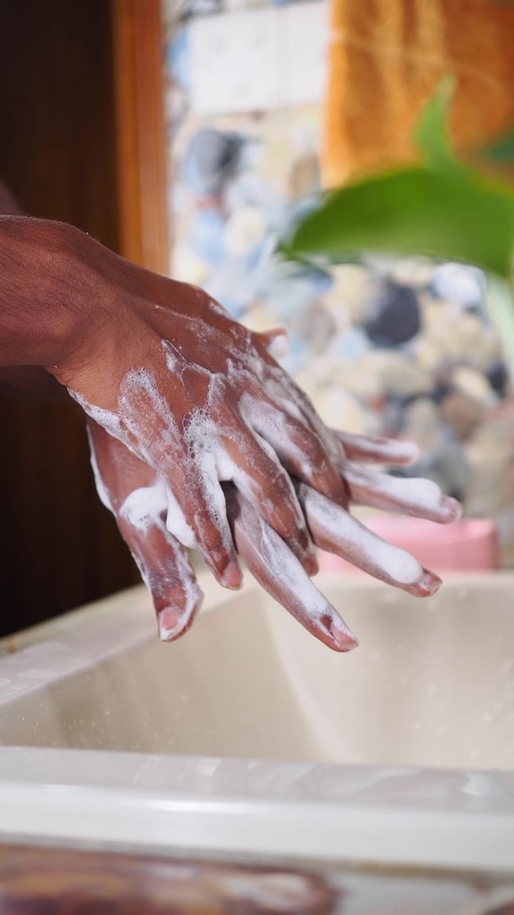 Primo piano di mani che si insaponano in un lavandino del bagno.