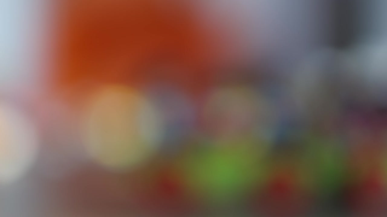 Sløret, ufokuseret lys baggrund med abstrakte farverige orange, blå og grønne lys.