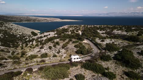 el movimiento cinematográfico de drones a la izquierda sigue una camioneta conduciendo, mostrando las maravillas de croacia en sus montañas y acompañada por el mar adriático en un hermoso día soleado