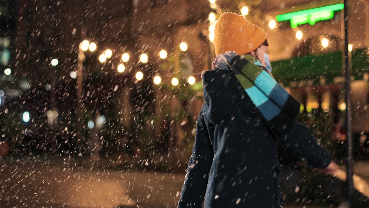 vista de cerca de un niño alegre caucásico parado en la calle en navidad mientras juega y trata de atrapar nieve