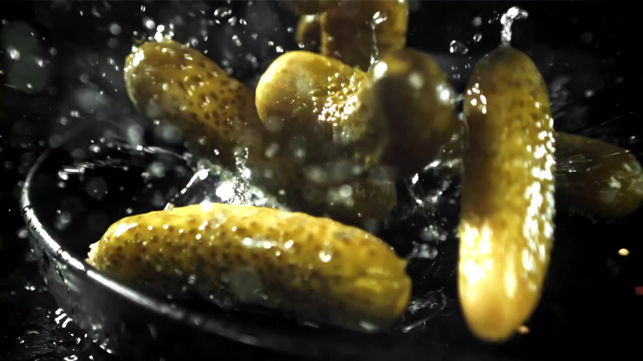Ferske sylteagurker som plasker ned i vann i sakte film