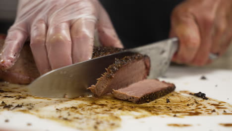 man evenly cuts slices of very lean texas barbecue beef brisket on messy cutting board, slow motion close up 4k