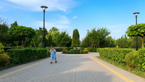 lovely kid wearing jeans stepping happily by the paved road. cute smiling toddler runs approaching camera. baby walking in the park.
