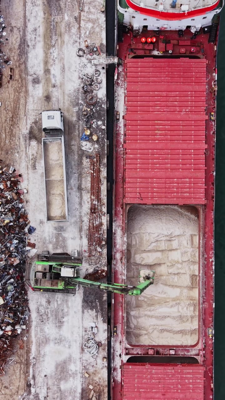 Scrap materials are loaded onto a large cargo ship at the port