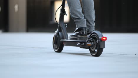 a young businessman drives his e-scooter through the city, close up