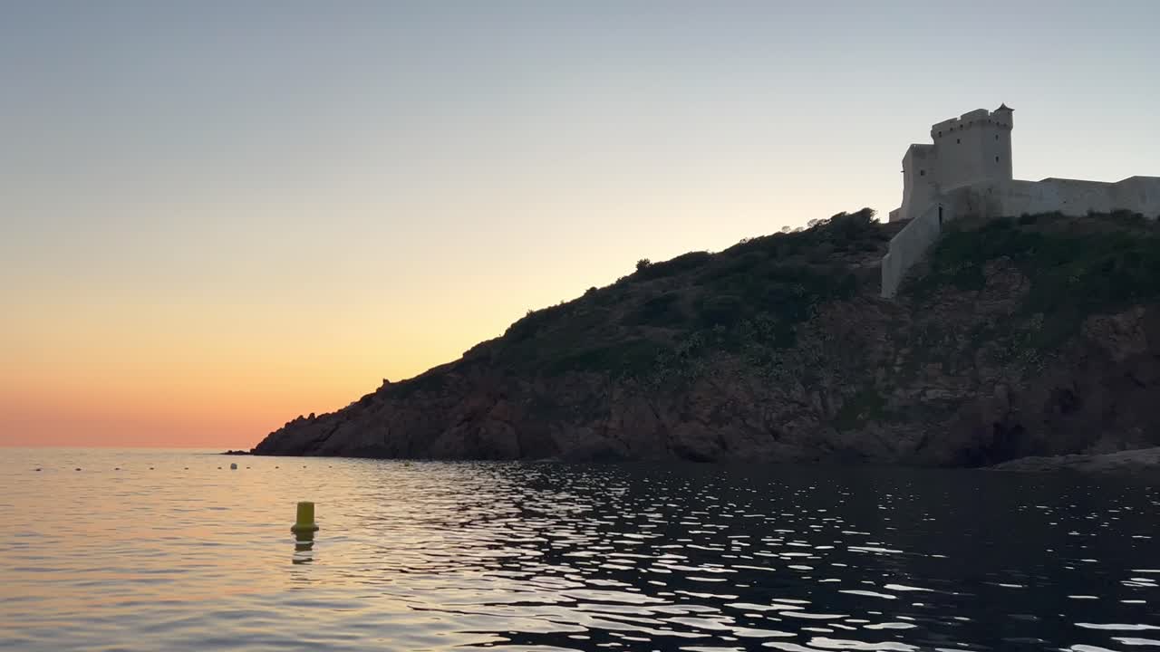 castillo de girolata al atardecer visto desde un barco de vela que recorre la isla de córcega en francia
