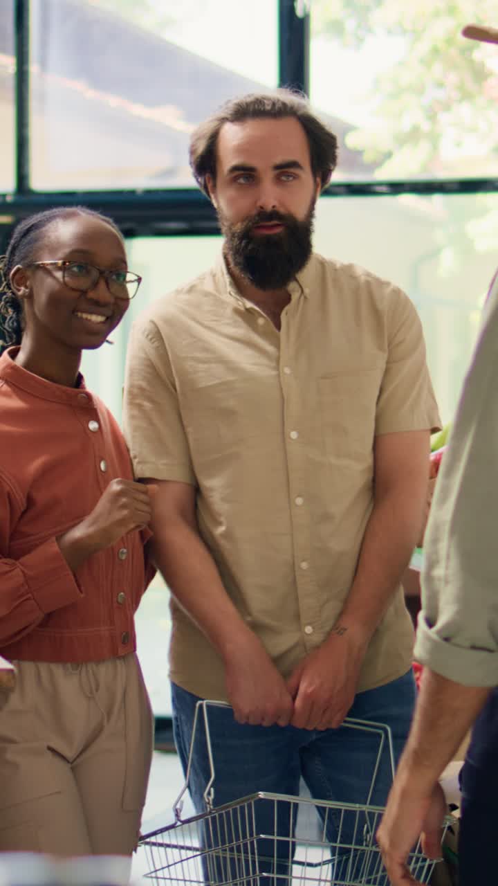 Vertical video Vendor shows ripe veggies to clients