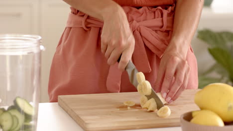woman slicing bananas on wooden cutting board in kitchen, preparing healthy meal