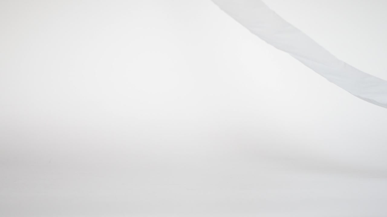 Slow motion of a toilet roll falling and rolling out of the camera frame, studio shot white background