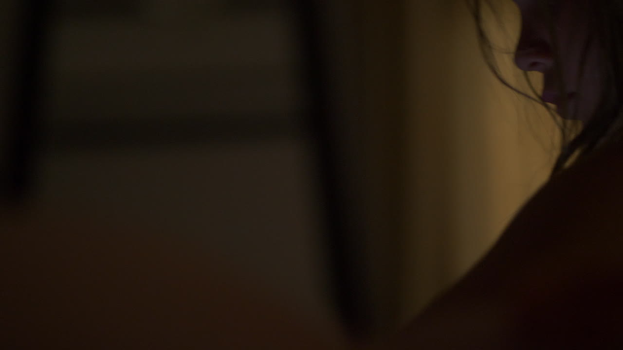 chica con problemas con el pelo desordenado mirando hacia abajo en una habitación oscura