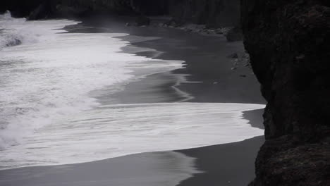 waves splash against shore on icelandic black sand beach