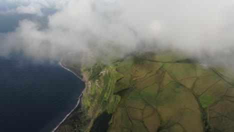 flying through low clouds above flores island in azores, aerial