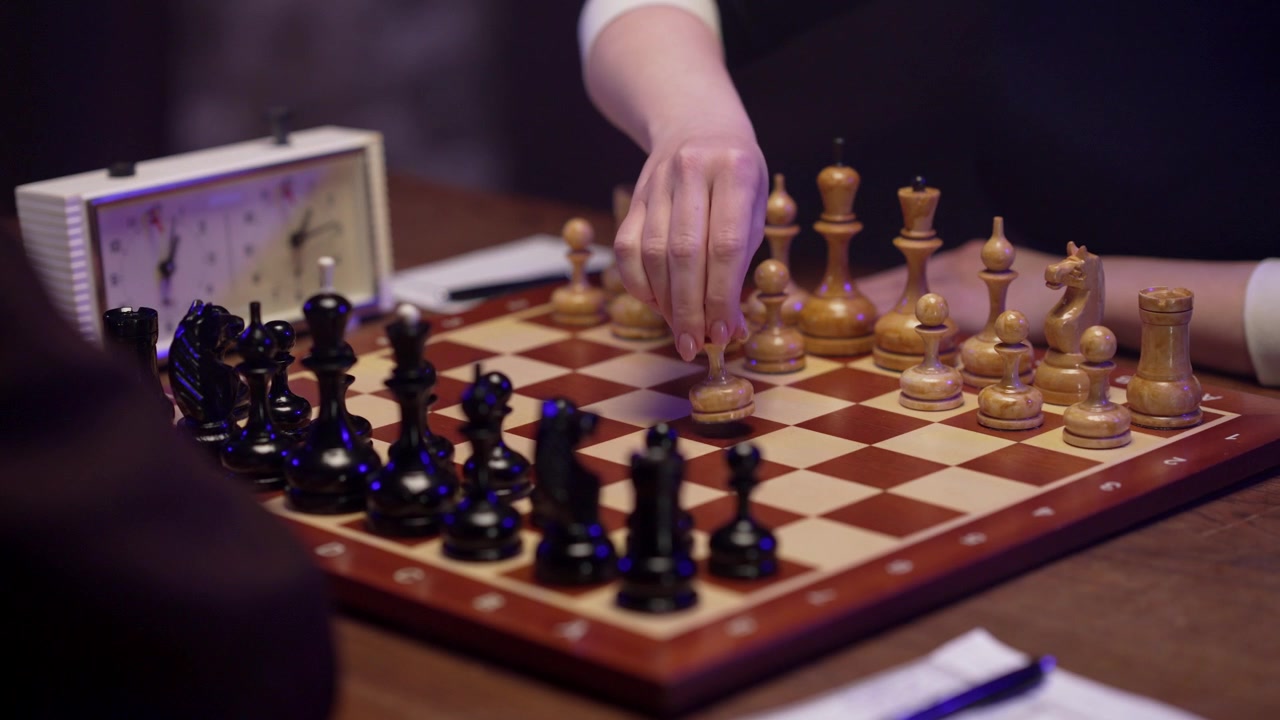 Joueur déplaçant un pion et appuyant sur la pendule d'échecs pendant la partie.