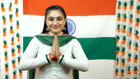 smiling indian girl greeting the guests and posing for the camera - independence day. tricolor background