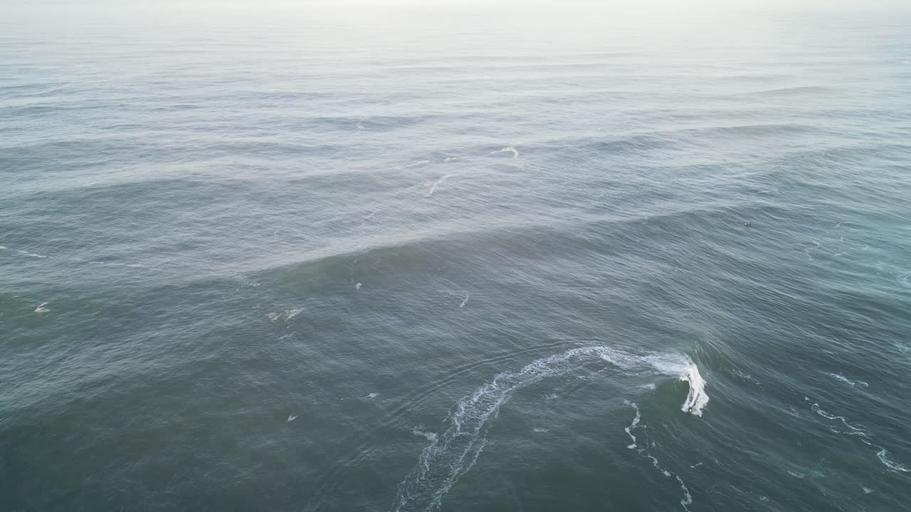 Waves rolling on the ocean surface near Farol Nazare, Portugal, shot from above
