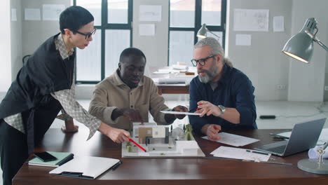 Team-of-Diverse-Architects-Discussing-Building-Model-in-Office