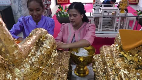 buddhist ceremony with gold leaf offering