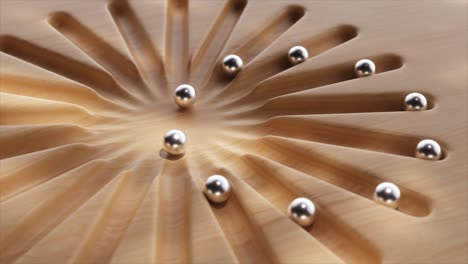 superficie de madera con trayectorias radiales y bolas metálicas