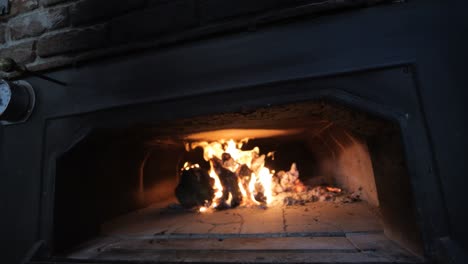 dolly shot of wood ablaze inside traditional wood fire pizza oven