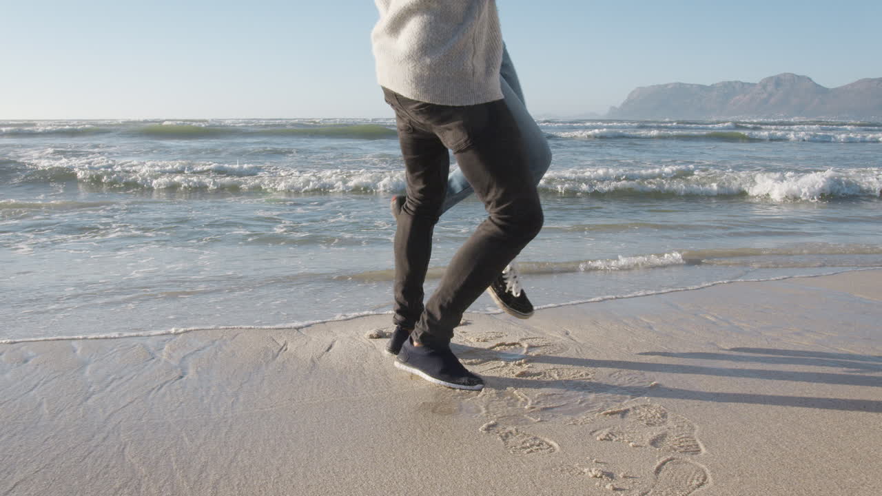 겨울 해변 에 있는 부부 가 진전 하는 파도 에서 도망치고 있다