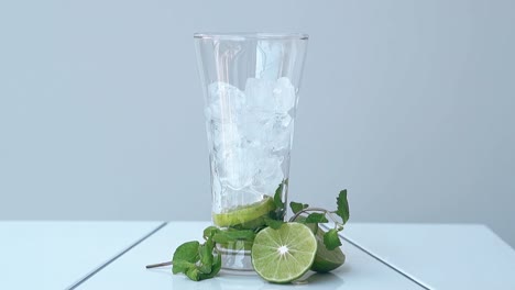 Un-Vaso-Alto-Y-Brillante-Lleno-De-Cubitos-De-Hielo-Se-Encuentra-Sobre-Una-Mesa-Blanca