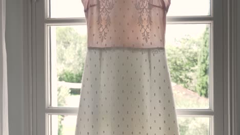 cámara mirando hacia arriba filmando el vestido de novia de la novia colgado en la ventana