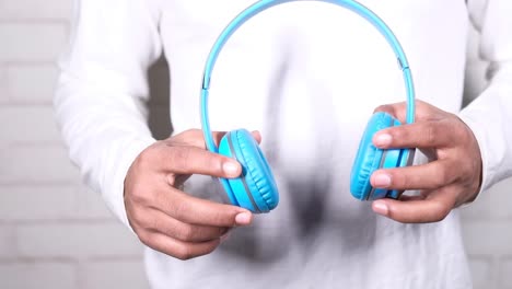 person holding blue headphones