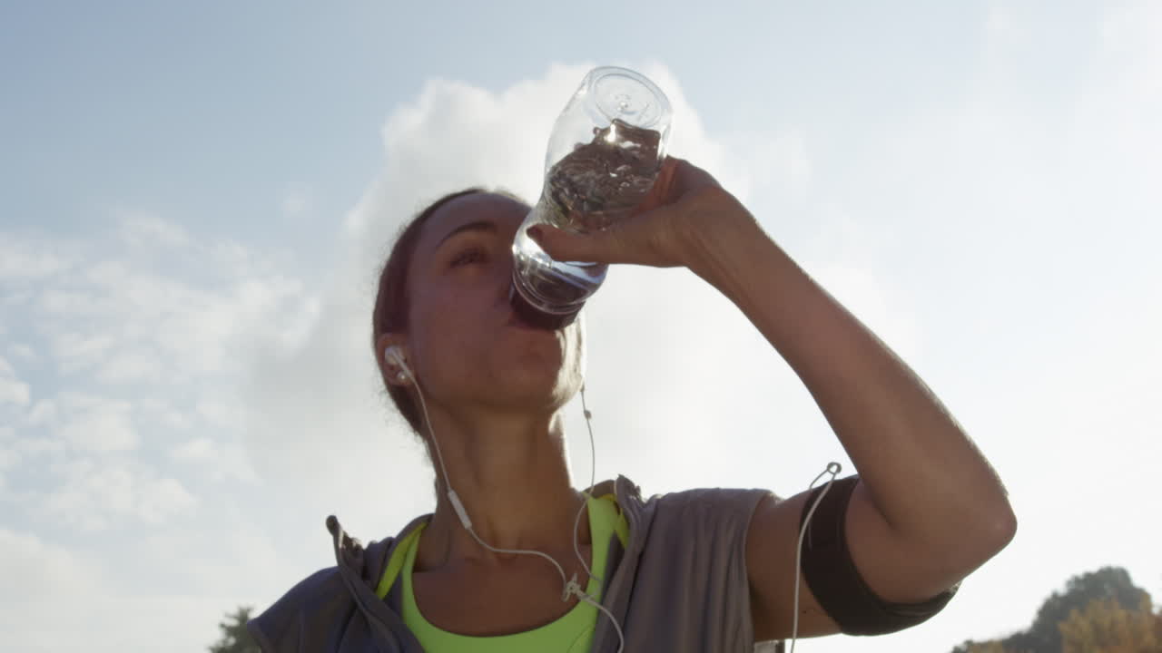 corredora mujer bebiendo botella de agua sol llamarada energía solar