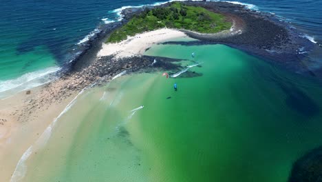 Drone-aerial-people-kitesurfing-sandbar-off-remote-ocean-beach-with-reef-waves-Island-Bendalong-Manyana-South-Coast-Australia-4K