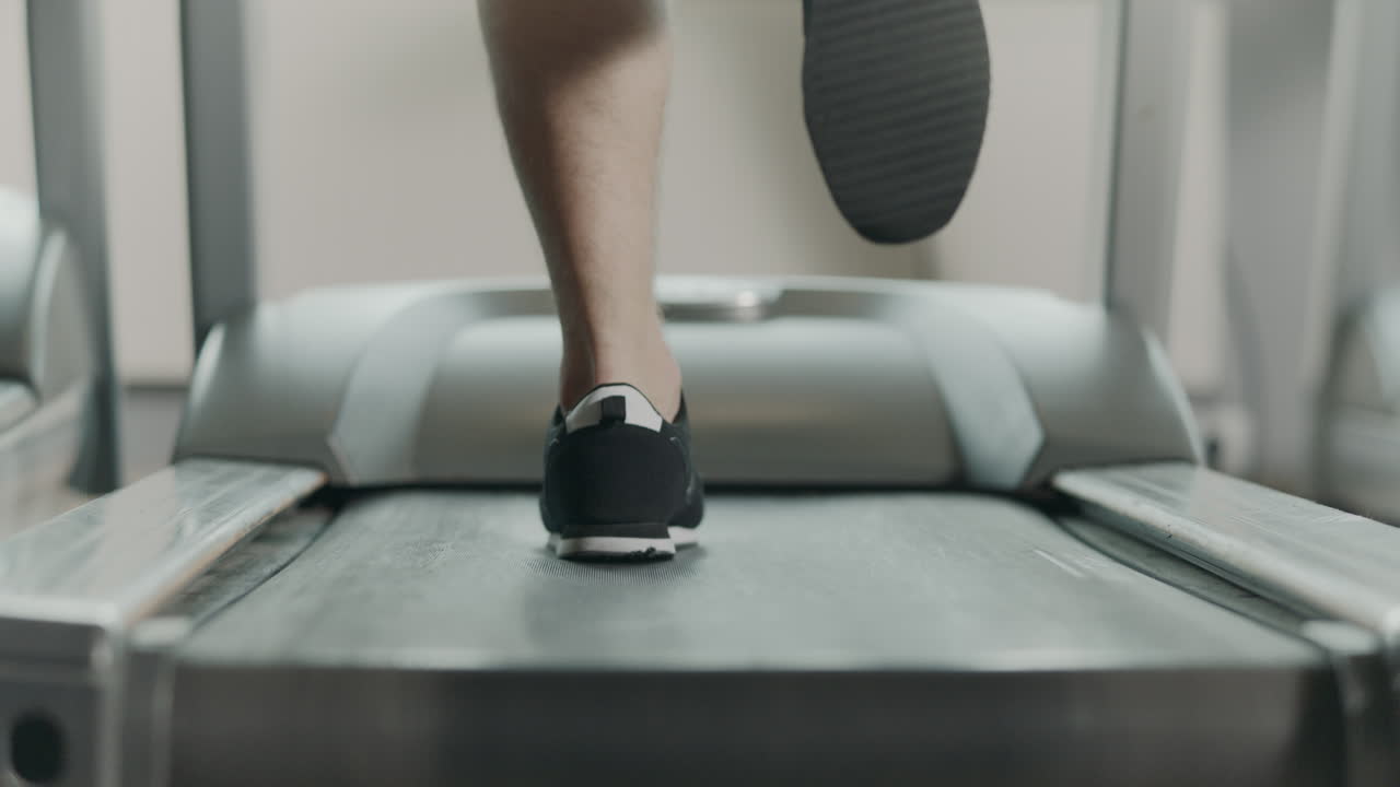 Closeup athletic feet running on treadmill in fitness gym.