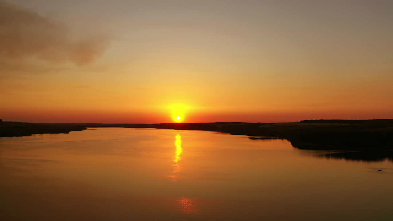 Amazing sunset over the water. Orange background from the setting sun. Golden path reflects on river in the evening.