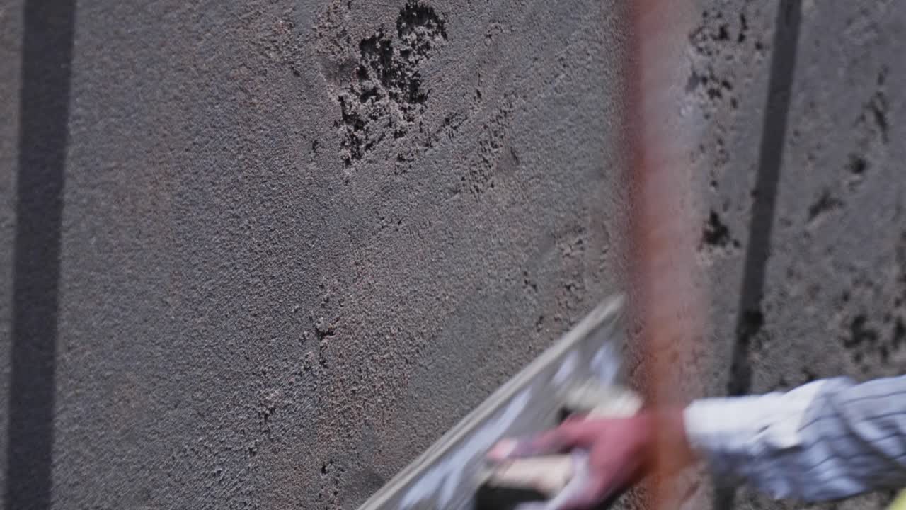 Pekerja menggunakan alat sekop dan alat perata kayu untuk plesteran dinding di lokasi konstruksi, Hyderabad, Telangana, India. Siang hari, rekaman stabil, 4K