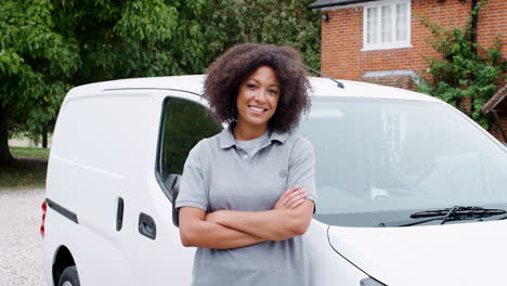 Young-black-female-tradesperson-standing-next-to-her-white-van-smiling-to-camera-crosses-her-arms,-close-up