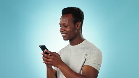 Man,-smile-and-texting-on-phone-in-studio-by-blue