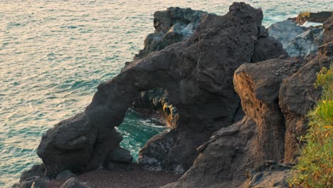 Oceanic-rock-arch-hangs-above-glowing-ocean-light-from-golden-hour