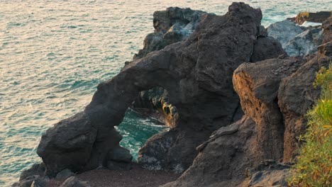 oceanic rock arch hangs above glowing ocean light from golden hour