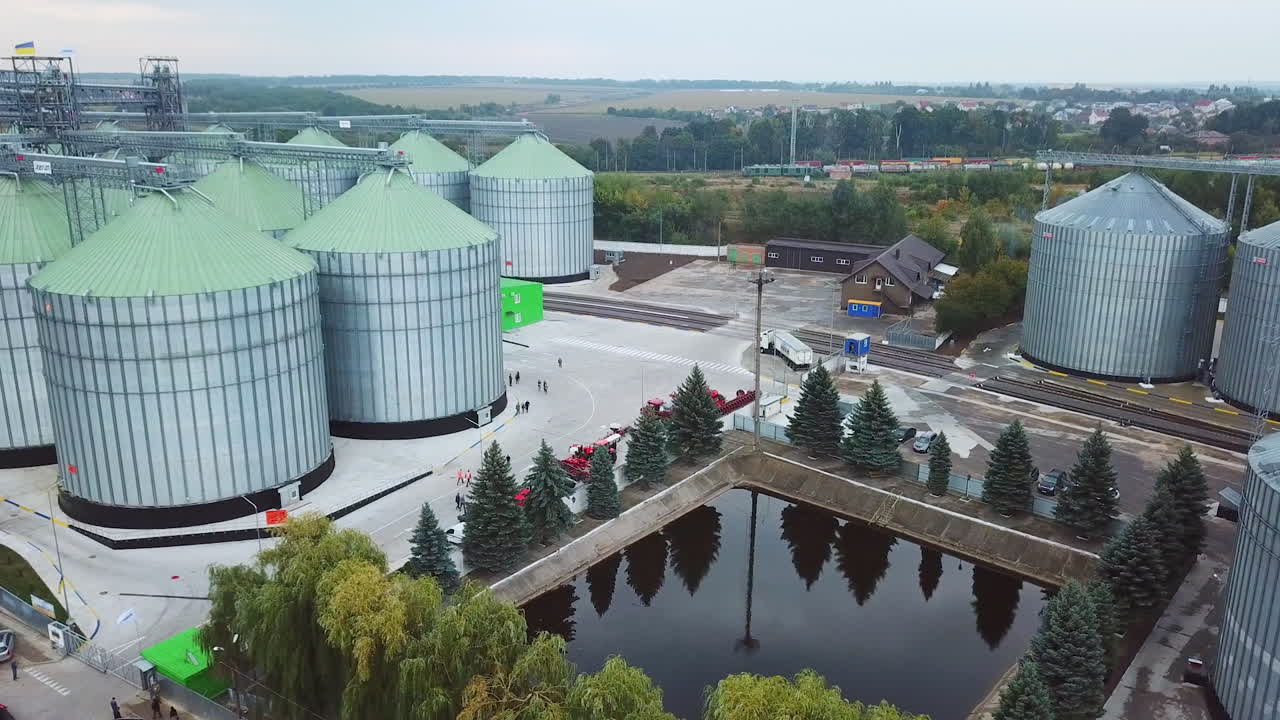 Flying above the modern elevator plant territory. Car park, artificial pond and railways locating at the industrial zone.