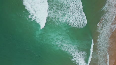 sea waves create frothy textures rolling sandy beach top view. ocean