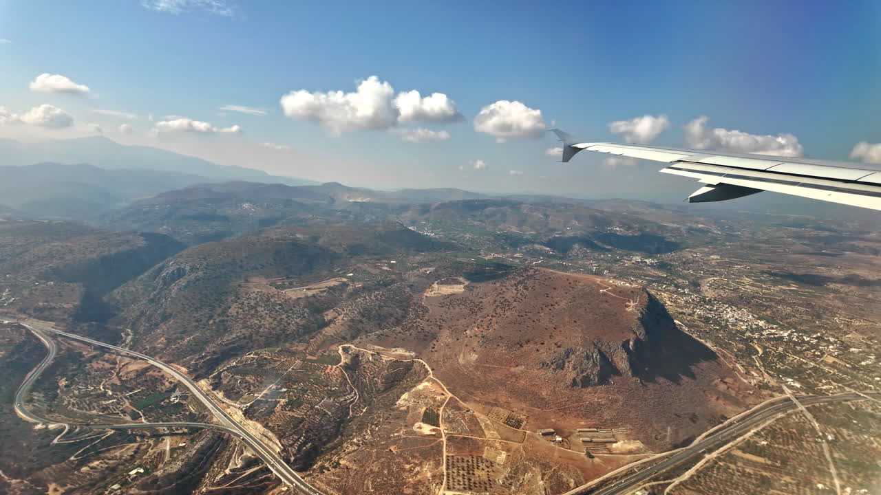 View of sky and ground from Airplane window during bright day over Crete city, Greece