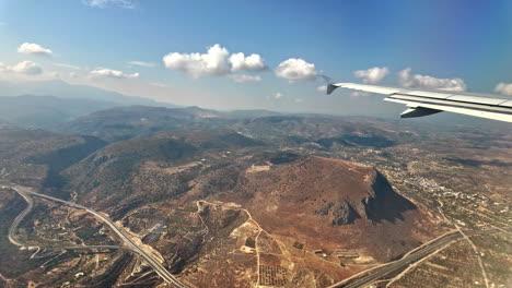 view of sky and ground from airplane window during bright day over crete city, greece
