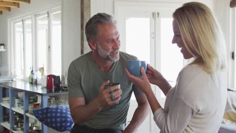 Relaxing-caucasian-mature-couple-drinking-coffee-and-talking-in-kitchen